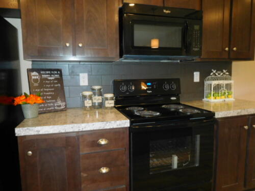 A kitchen with black appliances and granite counter tops.