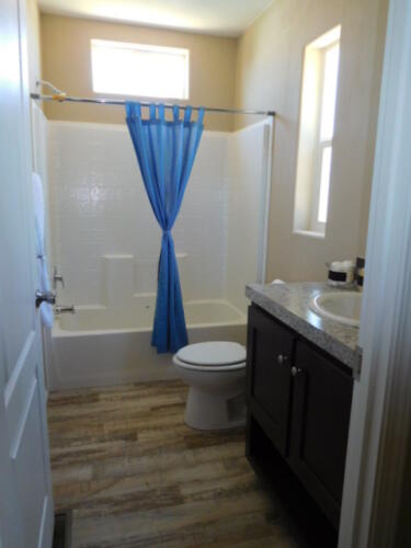 A bathroom with a blue shower curtain and toilet.