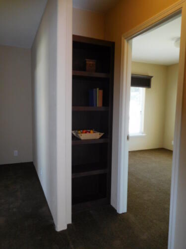 An empty room with a book shelf and a door.