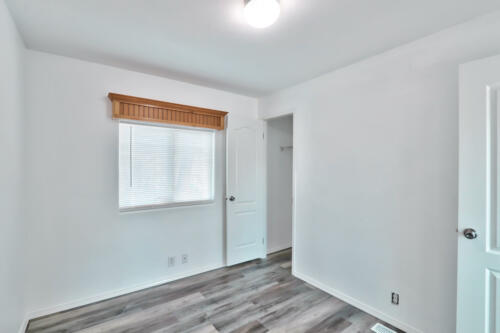 An empty room with white walls and hardwood floors.