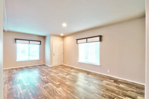 Empty living room with hardwood floors and a window.