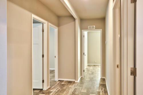 A hallway with wood floors and white walls.