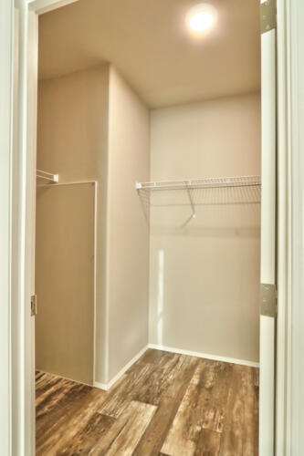A walk in closet in a room with hardwood floors.