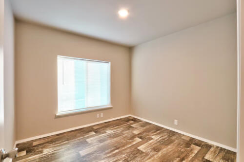 An empty room with wood floors and a window.