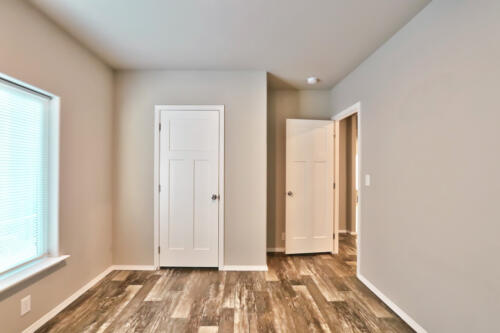 An empty room with wood floors and white doors.