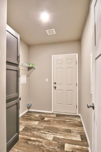A laundry room with wood floors and a door.