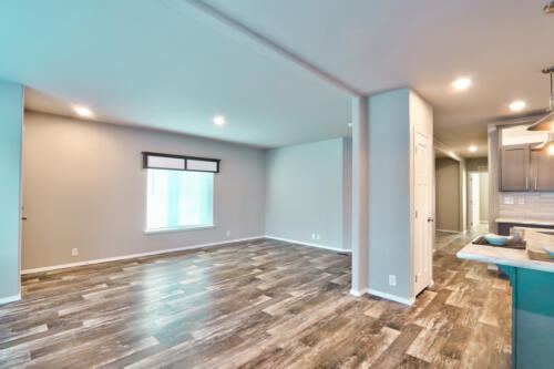 An empty living room with wood floors and gray walls.