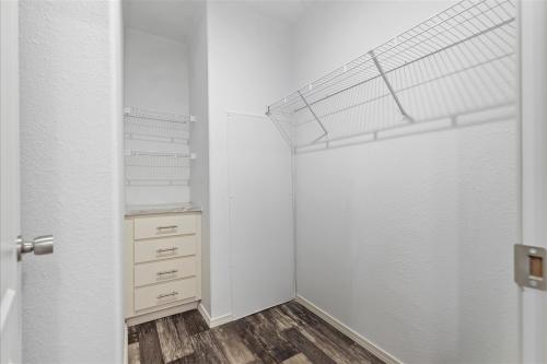A closet with white walls and wood floors.