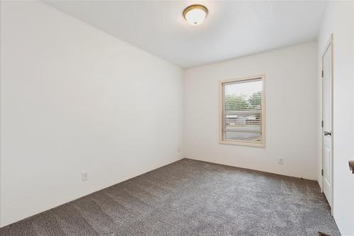 An empty room with gray carpet and a window.