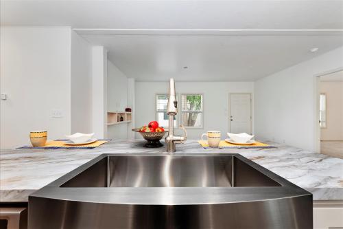 A kitchen with a stainless steel sink and marble counter tops.