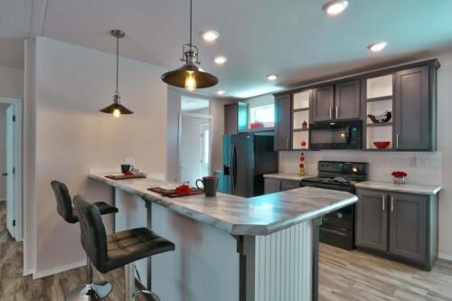 A kitchen with stainless steel appliances and a bar stools.