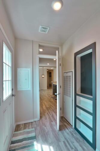 A hallway in a home with hardwood floors and a door.