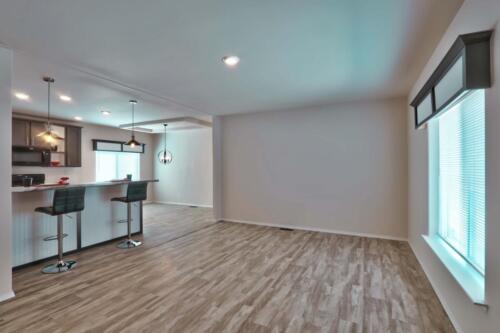 An empty living room with hardwood floors and a bar.