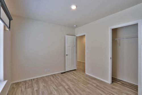 An empty room with hardwood floors and a closet.